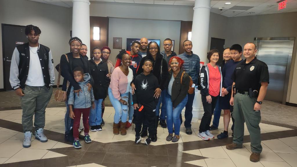 Group photo of several black and asian families and one white police officer at a GAPS police initiative event.